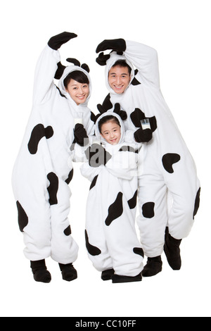 Family in cow costumes with glasses of milk playing around Stock Photo