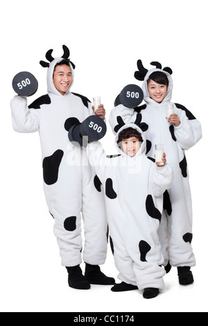 Family in cow costumes lifting dumbbells with glasses of milk Stock Photo