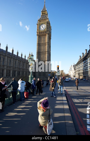 female tourists taking photos at the palace of westminster clock tower aka elizabeth big ben, st stephens tower London England Stock Photo