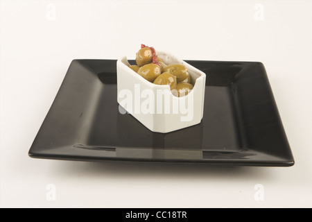 Stuffed olives in brine in white plate with white background. Stock Photo