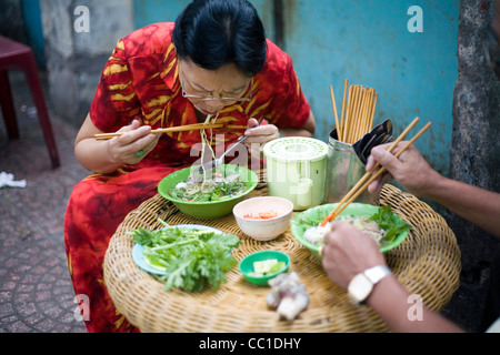 A couple eat Pho noodle soup for breakfast at a street side cafe, Ho Chi Minh City (formerly Saigon), Vietnam Stock Photo