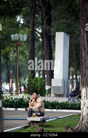 A man smokes a cigarette in a park after his breakfast, Ho Chi Minh City (formerly Saigon), Vietnam Stock Photo