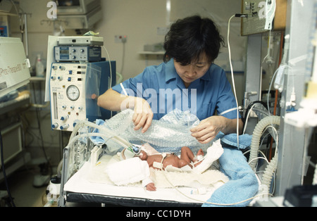 Nurse tending baby in neonatal intensive care unit Stock Photo