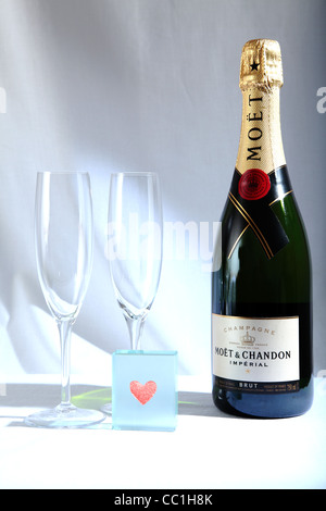 Bottle of Moet and Chandon champagne with two flutes and a red heart on glass block against white background Stock Photo