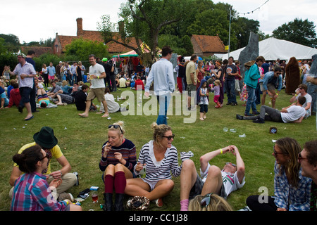 A group of people sit on the grass drinking and talking at the Standon Calling Festival in Hertfordshire Stock Photo