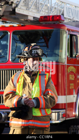 A firefighter in front of a ladder fire truck Stock Photo