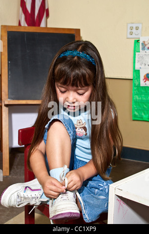 Interracial inter racial 4-5 year years old girl learning to tie her shoes in clas sroom. MR  © Myrleen Pearson Stock Photo