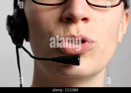 Young woman is talking, on the phone, Internet, Voice over IP, using a headset. Closeup of the face. Stock Photo