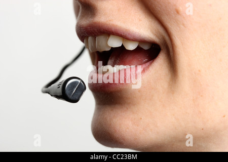 Young woman is talking, on the phone, Internet, Voice over IP, using a headset. Closeup of the face. Stock Photo