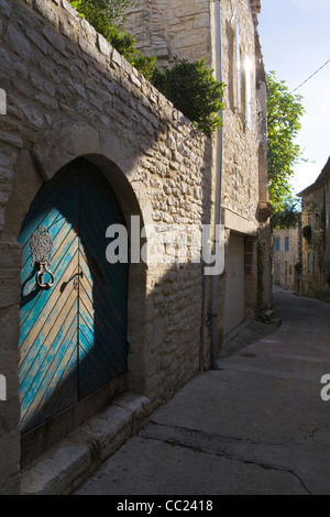 A blue painted arched doorway, lit by afternoon sun on the stone streets of Vezenobres, Gard, France Stock Photo
