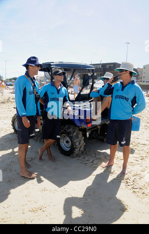 A group of professional lifeguards ( full-time) wearing blue kit with their beach quad bike on Bondi Beach Stock Photo