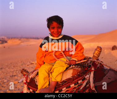 Egyptian boy sitting on a Camel near the Pyramids, Cairo, Egypt Stock Photo