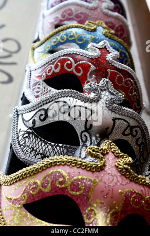 Masquerade masks for the ball, hanging in a row on a wall Stock Photo