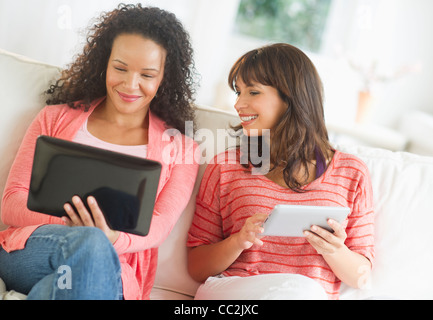 USA, New Jersey, Jersey City, Two women sitting on sofa using digital tablets Stock Photo