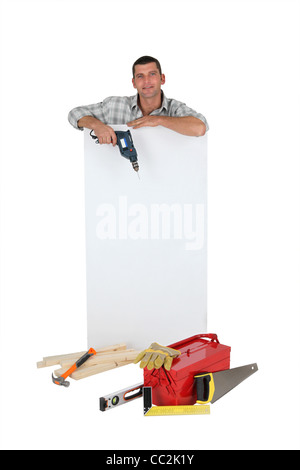 Man holding drill next to blank advertising panel Stock Photo