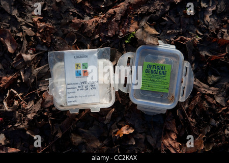 Small geocache tupperware box and lid, open and showing log-book. Stock Photo