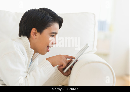 USA, New Jersey, Jersey City, Boy (12-13) using digital tablet on sofa Stock Photo