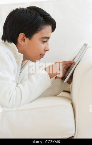 USA, New Jersey, Jersey City, Boy (12-13) using digital tablet on sofa Stock Photo