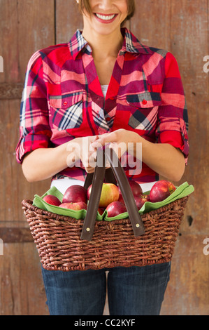 USA, New Jersey, Jersey City, Smiling woman holding basket full of apples Stock Photo