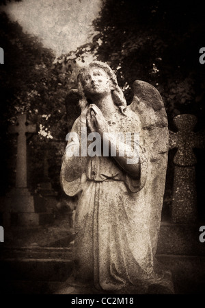 Statue of an female angel praying in Brompton Cemetery, London Stock Photo