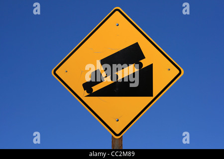 steep road sign with a truck driving down a steep downgrade in black and yellow on blue sky background Stock Photo