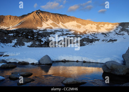Mountain ridge in the Sierra Nevada mountains lit up by evening light and reflected in a stream Stock Photo