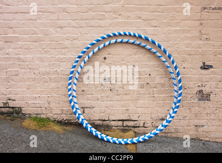 two blue and white hula hoops resting against painted brick wall Stock Photo