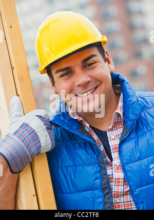 USA, New Jersey, Jersey City, Construction worker carrying planks on construction site Stock Photo