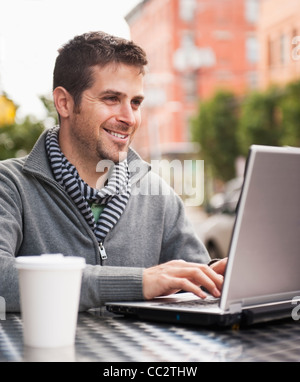 USA, New Jersey, Jersey City, Man with laptop sitting in outdoor cafe Stock Photo