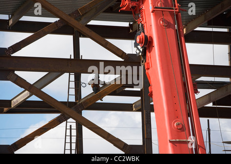 USA, New York City, Construction worker working on unfinished structure, red crane in foreground Stock Photo