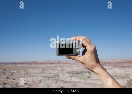 USA, Arizona, Winslow, Hand of woman holding camera up against blue sky Stock Photo