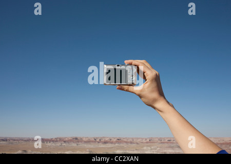 USA, Arizona, Winslow, Hand of woman holding camera up against blue sky Stock Photo