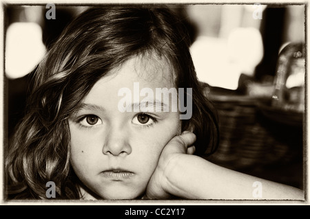 Cute portrait of a young 5 year old brunette girl pouting with big brown eyes gazing into the camera. [room for copy] artisan Stock Photo