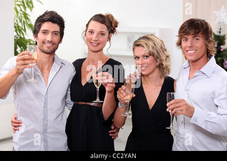 four people toasting in front of a Christmas tree Stock Photo