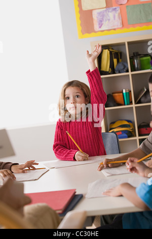 Schoolgirl with hand raised in classroom at primary school Stock Photo ...