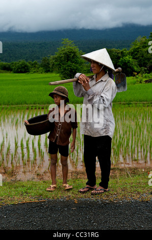 Khmer farmers, mother wearing a conical hat & daughter w/ a bamboo basket, rice paddy in background, Kampot Province, Cambodia. credit: Kraig Lieb Stock Photo