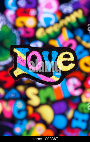Embroidery iron on patches of Multicoloured Love, Peace, Happy, Smile, and Groovy words on a black background Stock Photo