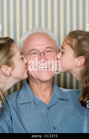 Portrait of two girls (8-9, 14-15) kissing grandfather Stock Photo