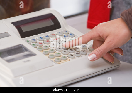 Close-up image of a shop-assistant's hand pressing a key of an electronic cash register in a shop. Stock Photo