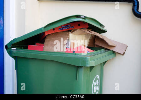 Green wheelie bin overflowing with domestic rubbish awaiting collection ...