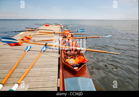 Single-scullers and coxless four at the pontoon jetty for a lunch break during a youth activity week in Rungsted Rowing Club, North Sealand, Denmark. Stock Photo