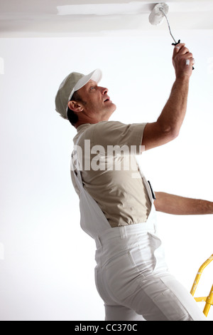 Man repainting ceiling with roller Stock Photo