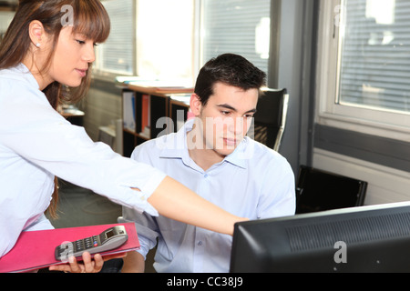 Woman explaining something on a computer to her colleague Stock Photo