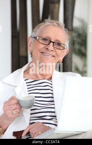 Old lady with laptop and coffee Stock Photo