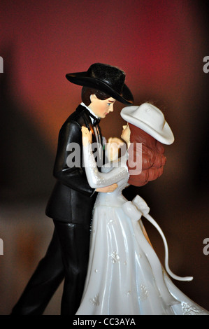 A wedding cake topper with a country and western style sits on top of a wedding cake. Stock Photo