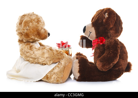 Photo of a boy teddy bear giving a girl teddy a gift, isolated on a white background. Stock Photo