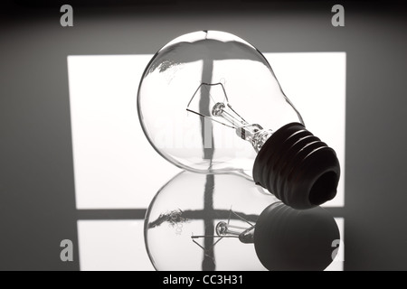 Lightbulb on a grey glass background on the window reflection. Stock Photo