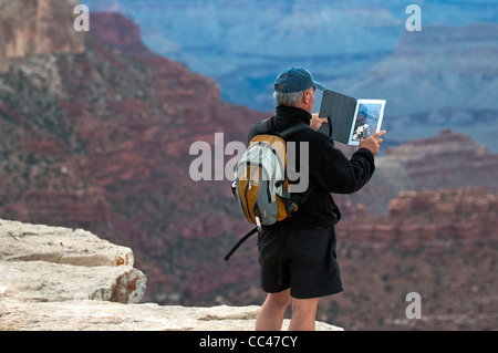A man using an Apple I Pad to photograph the Grand Canyon South Rim in Arizona Stock Photo