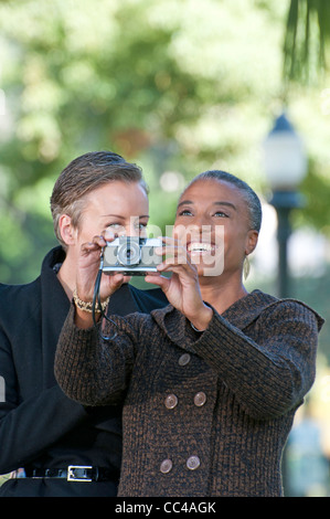 two middle aged woman have fun in the park taking photos Stock Photo