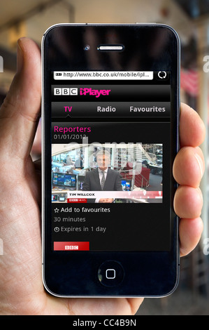 Watching the BBC News Channel on the BBC iPlayer on an Apple iPhone 4 smartphone via a public Wi-Fi hotspot Stock Photo